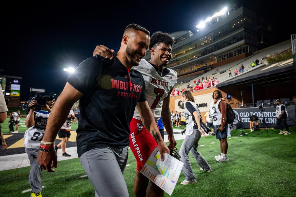 Tight ends coach Gavin Locklear and senior tight end Justin Joly smile while walking off the field together after the game against Wake Forest in Allegacy Stadium on Thursday, Sept. 11, 2025. Joly caught two touchdowns. The Wolfpack beat the Demon Deacons 34-24.