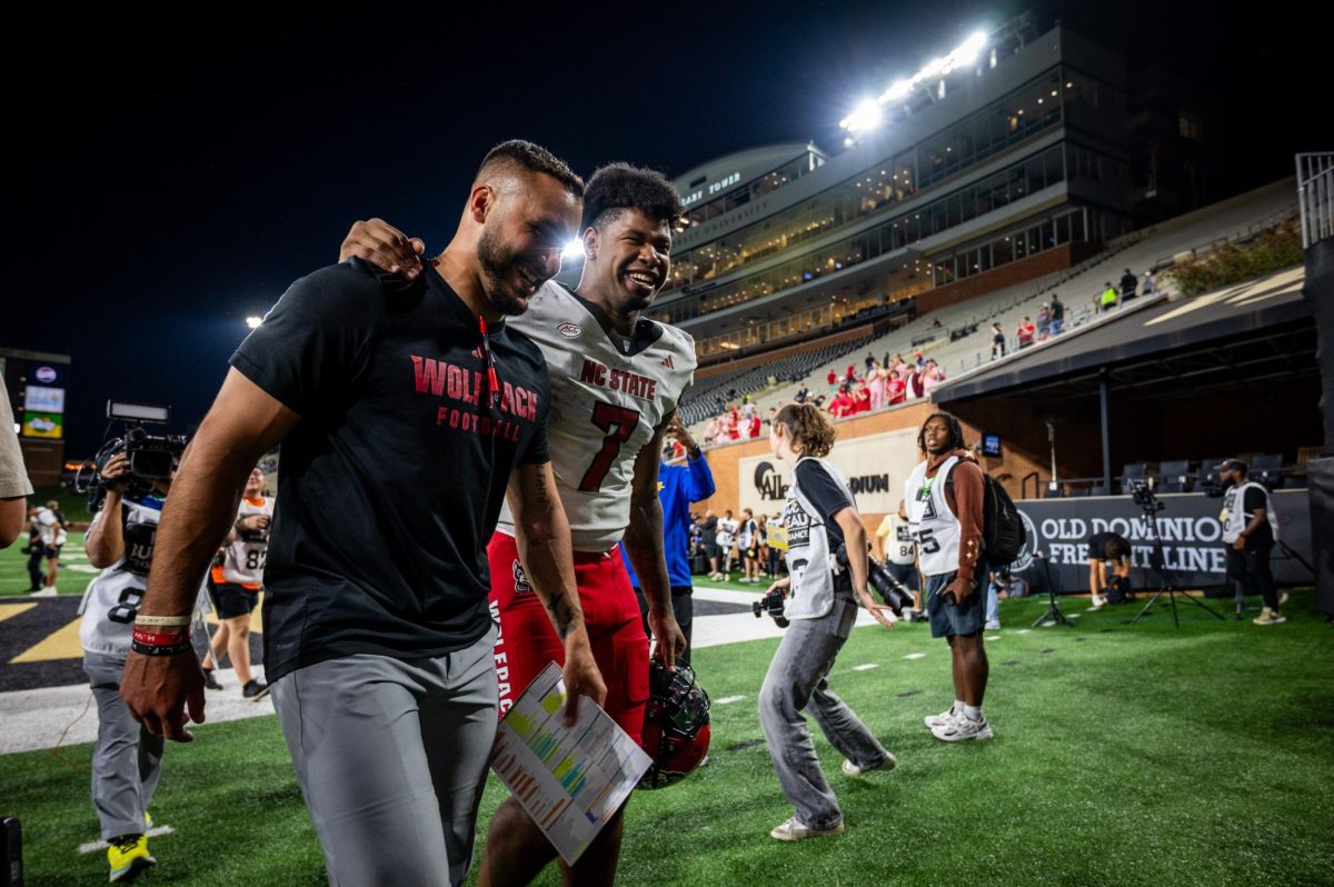 Tight ends coach Gavin Locklear and senior tight end Justin Joly smile while walking off the field together after the game against Wake Forest in Allegacy Stadium on Thursday, Sept. 11, 2025. Joly caught two touchdowns. The Wolfpack beat the Demon Deacons 34-24.