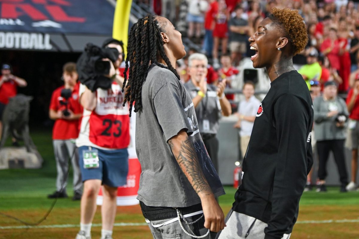 Former NC State Women's basketball players Aziaha James and Saniya Rivers cheer while leading fans in the Wolfpck chant before the game against Virginia Tech at Carter-Finley Stadium on Saturday, Sept. 27, 2025. NC State lost to Virginia Tech 23-21.