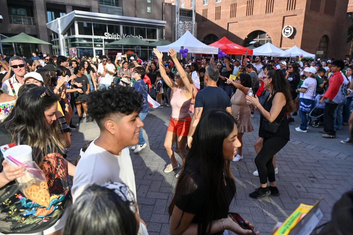 Festivalgoers dance together in a circle during La Fiesta del Pueblo at Fayetteville Street Historic District on Sunday, Sept. 21, 2025. The event, which draws thousands annually, is organized by El Pueblo to celebrate the pride and resilience of the Latine community.