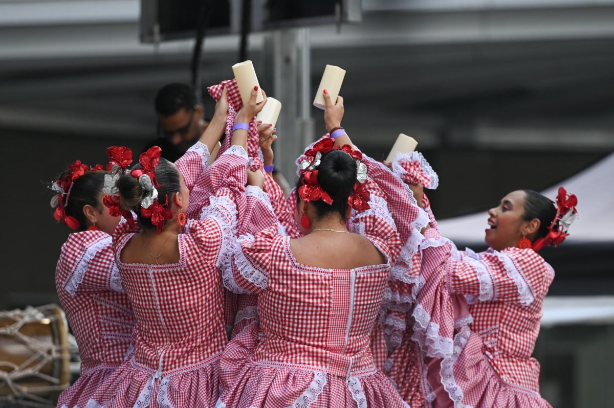 Colombian dance group Cumbión Colombiano lift unlit candles on stage as part of a dance routine during La Fiesta del Pueblo at Fayetteville Street Historic District on Sunday, Sept. 21, 2025. The event, which draws thousands annually, is organized by El Pueblo to celebrate the pride and resilience of the Latine community.