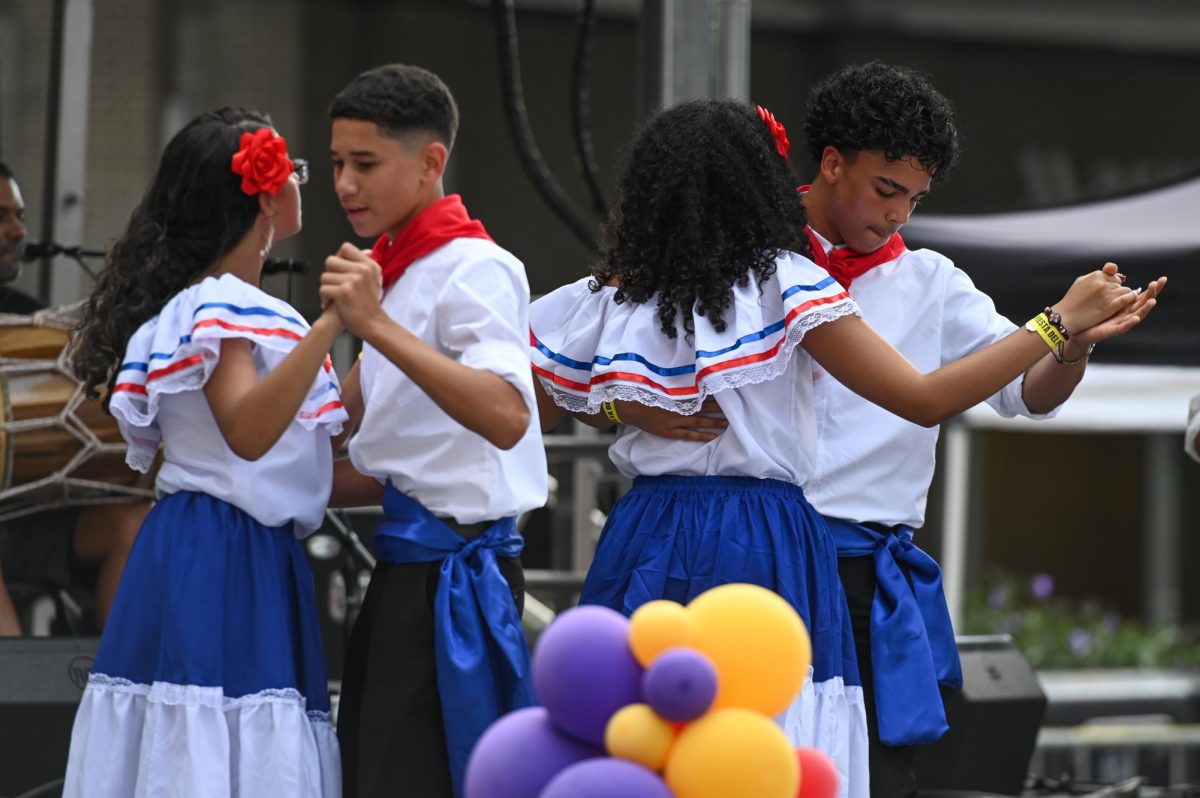Dancers perform with the traditional merengue band Zona Típica on stage during La Fiesta del Pueblo at Fayetteville Street Historic District on Sunday, Sept. 21, 2025. The event, which draws thousands annually, is organized by El Pueblo to celebrate the pride and resilience of the Latine community.