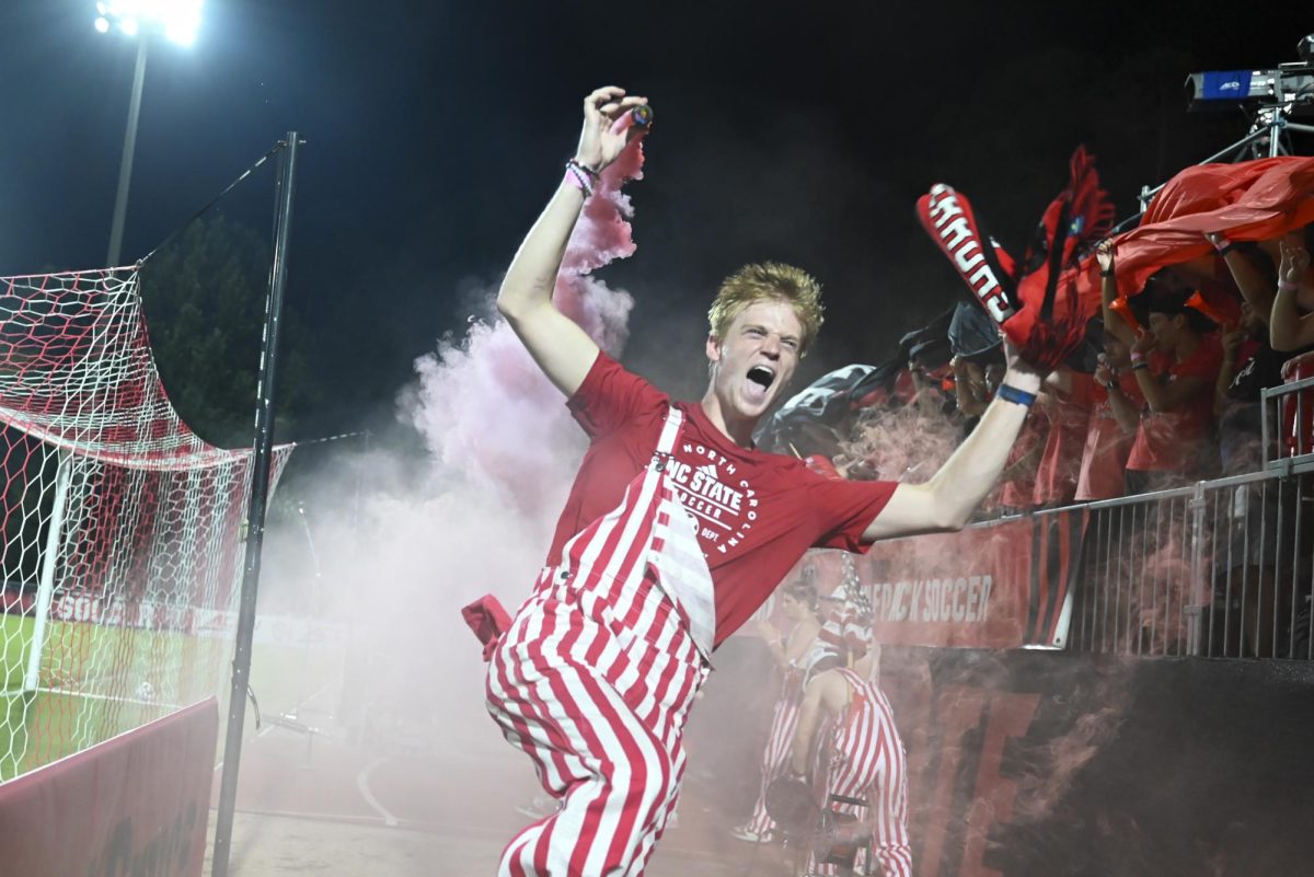 Thomas Sutton, a fourth-year studying biology and member of the Red Terrors, hypes up the student section during the soccer match against UNC-Chapel Hill at Dail Soccer Field on Friday, Sept. 5, 2025. This game broke the attendance record with over 4,000 attendees being in the stadium. NC State tied with UNC 0-0.