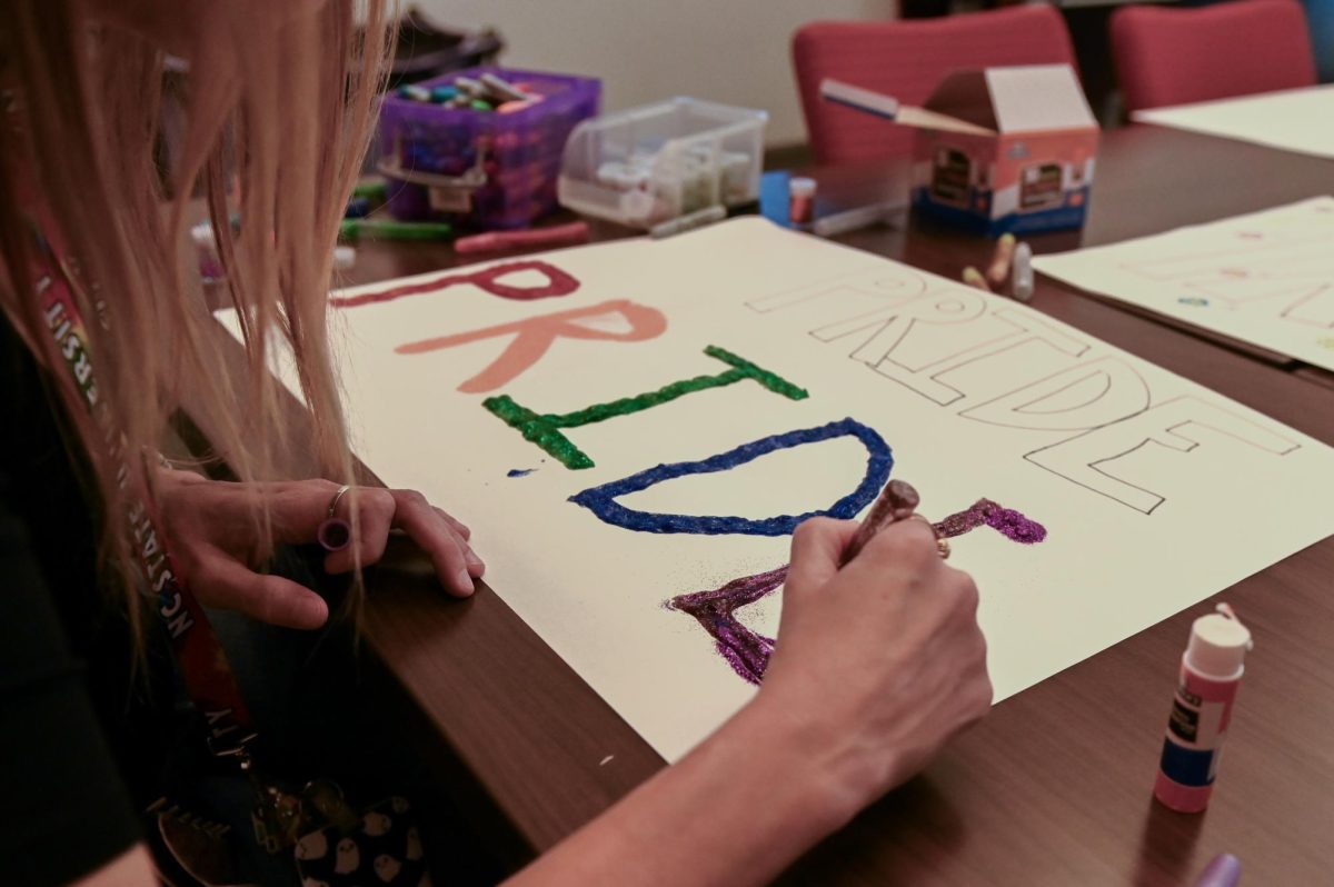 Kelly McConkey, a counselor at The Counseling Center, paints a pride sign in glitter at the PrideFest poster-making event at Talley Student Union on Wednesday, Sept. 24, 2025. The poster-making event is one of the events the Pride Center holds to prepare for PrideFest, which is on Oct. 7.