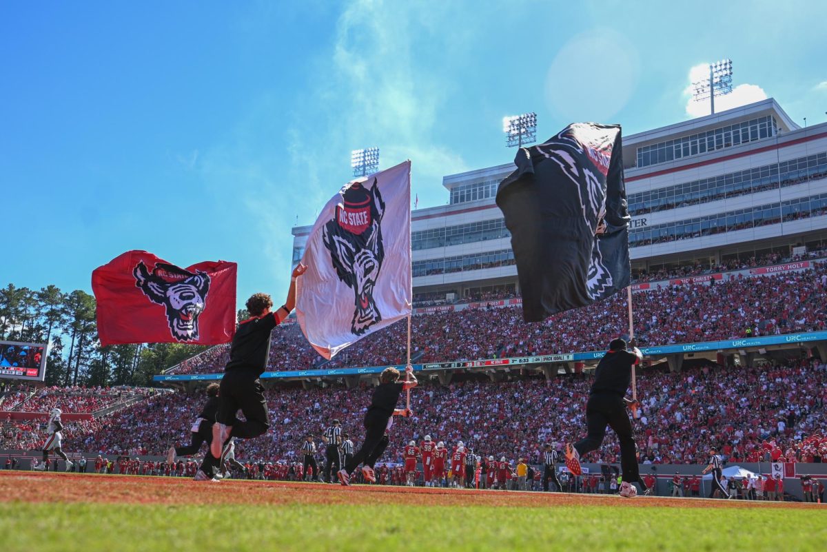 NC State cheer team runs across the field with flags after a touchdown during the game against the Fighting Camels at Carter-Finley Stadium on Saturday, Oct. 4, 2025. The Wolfpack totaled 236 yards in rushing.. The Wolfpack defeated the Fighting Camels 10-56.