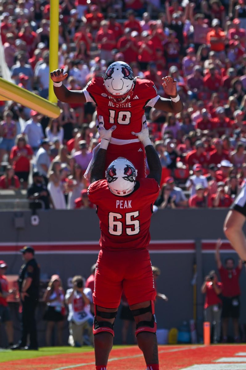 Redshirt junior offensive tackle Jacarrius Peak lifts up freshman quarterback Will Wilson after a touchdown during the game against the Fighting Camels at Carter-Finley Stadium on Saturday, Oct. 4, 2025. Wilson rushed 6 yards for a touchdown. The Wolfpack defeated the Fighting Camels 10-56.
