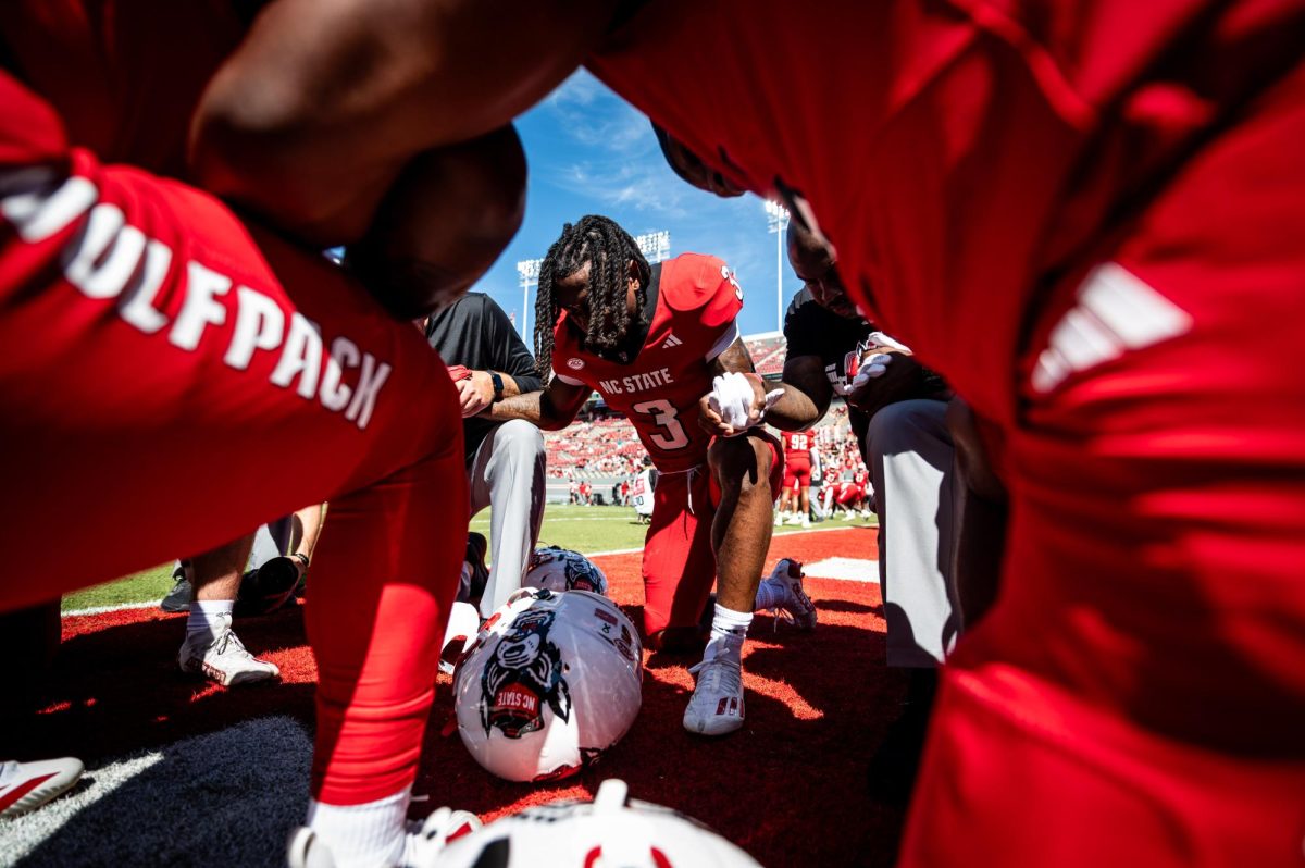 Redshirt sophomore running back Hollywood Smothers kneels in prayer with teammates before the game against Campbell in Carter-Finley Stadium on Saturday, Oct. 4, 2025. The Wolfpack beat the Camels 56-10.