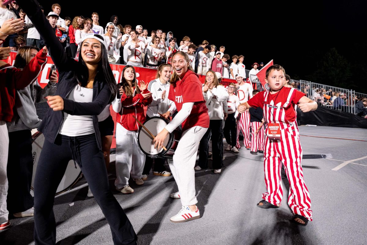 Senior goalkeeper Olivia Pratapas of the NC State Women's Soccer team smiles while playing the drums in the Red Terrors student section during the game against Clemson in Dail Soccer Stadium on Friday, Oct. 10, 2025. NC State defeated Clemson 1-0.