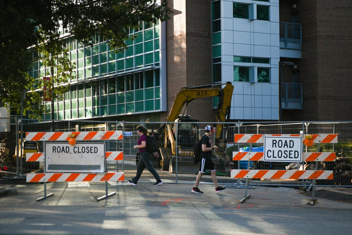 Alicia High, a second-year in chemical engineering, and Philip McKay, a fourth-year in computer science, walk past road closure signs on Morrill Dr. on Wednesday, Sept. 24, 2025. Morrill Dr. will be impacted by a water line replacement project that will carry into 2026.