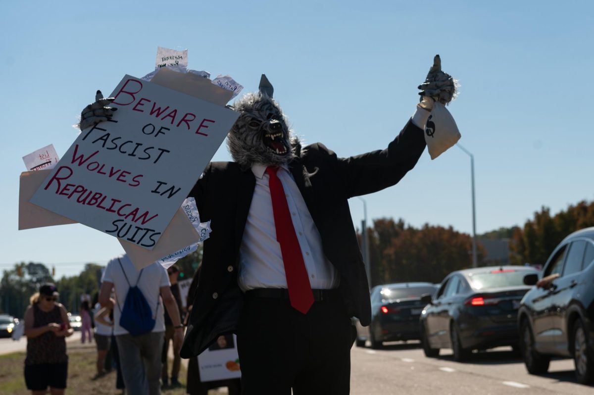 Rod H. holds a sign while dressed in a wolf costume during the No Kings protest on Capital Boulevard in Raleigh, NC, on Saturday, Oct. 18, 2025. The nationwide No Kings protests were organized in response to the recent policies and actions of President Donald Trump’s administration.
