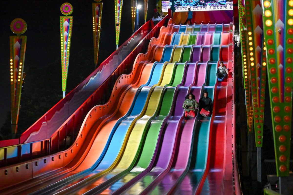 Finai Jackson, Kayshawn Parker and Isaiah Harrison from Savannah, Georgia, take a ride down the fair's giant slide during the North Carolina State Fair on Oct. 22, 2025. The annual N.C. State Fair draws large crowds to Raleigh.