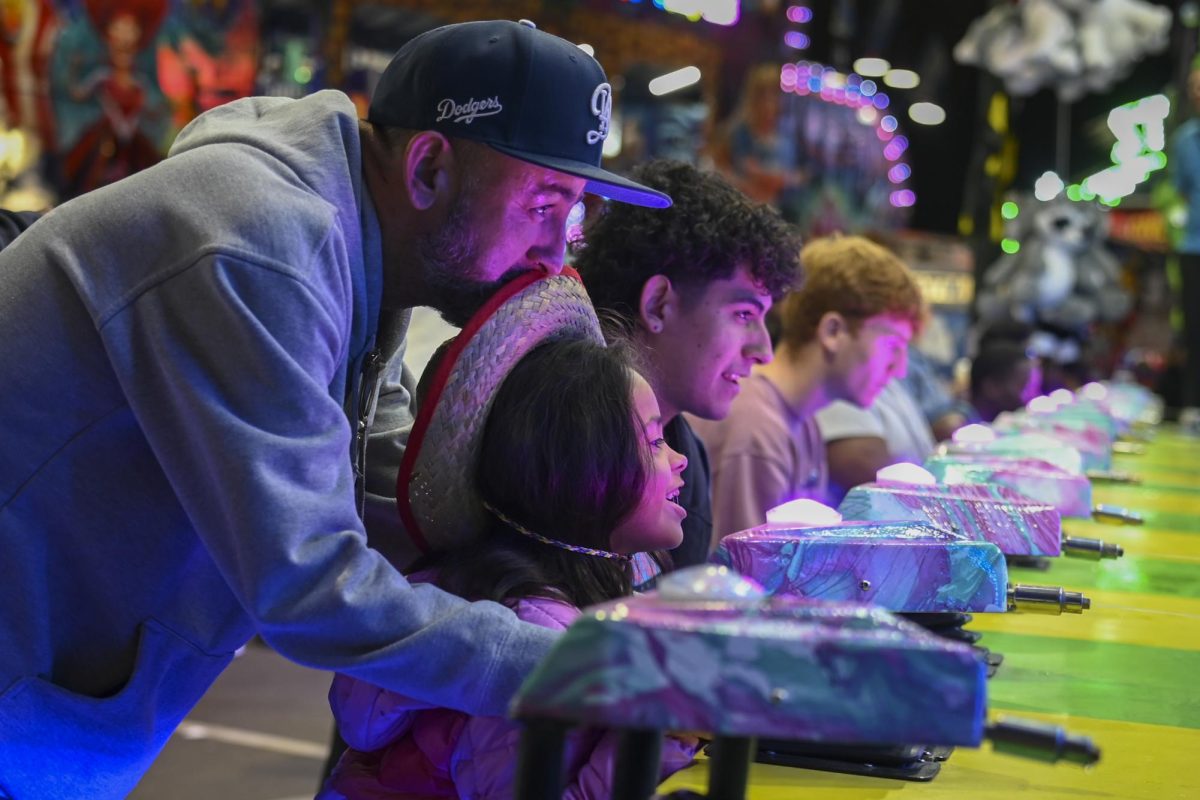 Angel Vassquez and his daughter from Los Angeles, California enjoy a game at the North Carolina State Fair in Raleigh on Wednesday, Oct. 22, 2025. The object of the game the pair played was to shoot the most water to knock the clown down.