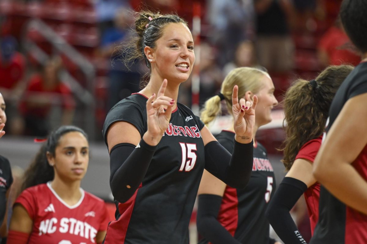 Senior middle blocker Lily Cropper holds up “wolfies” after the game against Florida State at Reynolds Coliseum on Sunday, Oct. 5, 2025. Cropper got two kills. NC State beat Florida State 3-2.