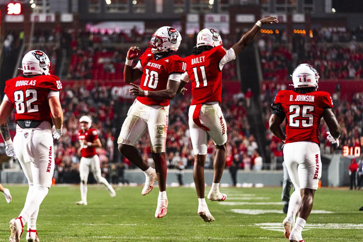 Freshman quarterback Will Wilson and sophomore quarterback CJ Bailey jump together in celebration after scoring a touchdown during the game against Florida State at Carter-Finley Stadium on Friday, Nov. 21, 2025. Wilson scored one touchdown. NC State beat Florida State 21-11.