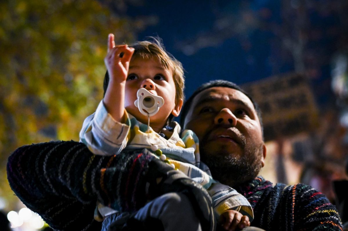 Protester Martin Labra and his child look up at a news helicopter in downtown Raleigh during the "No Border Patrol in Raleigh" protest on Tuesday, Nov. 18, 2025. The protest was organized by the social organizations Party For Socialism and Liberation, Nuestro Barrio Cafe, PalyYouthNC and 50501NC.