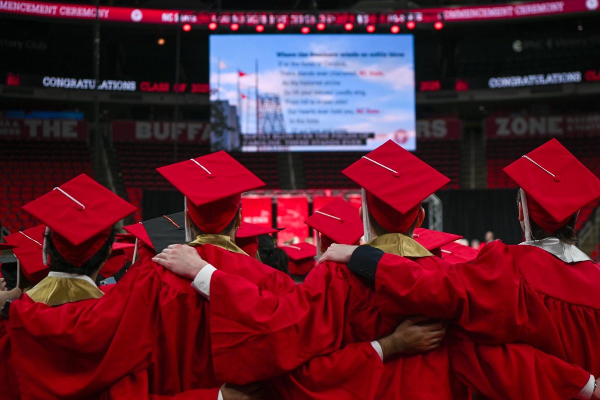 Newly graduated students join arms and sing NC State’s alma mater during the Fall Commencement Ceremony in the Lenovo Center on Saturday, Dec. 13, 2025. During the ceremony, graduates from all academic colleges including Engineering, Humanities and Social Sciences, Design and Agriculture and Life Sciences were recognized for their achievements.