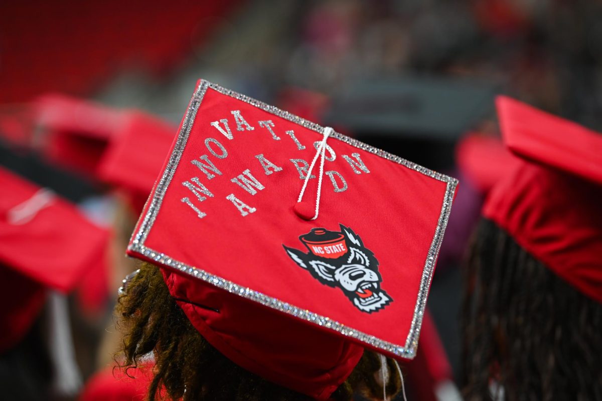 A student with a decorated cap sits during the Fall Commencement Ceremony in the Lenovo Center on Saturday, Dec. 13, 2025. The Fall Commencement honors both summer and fall 2025 graduates.