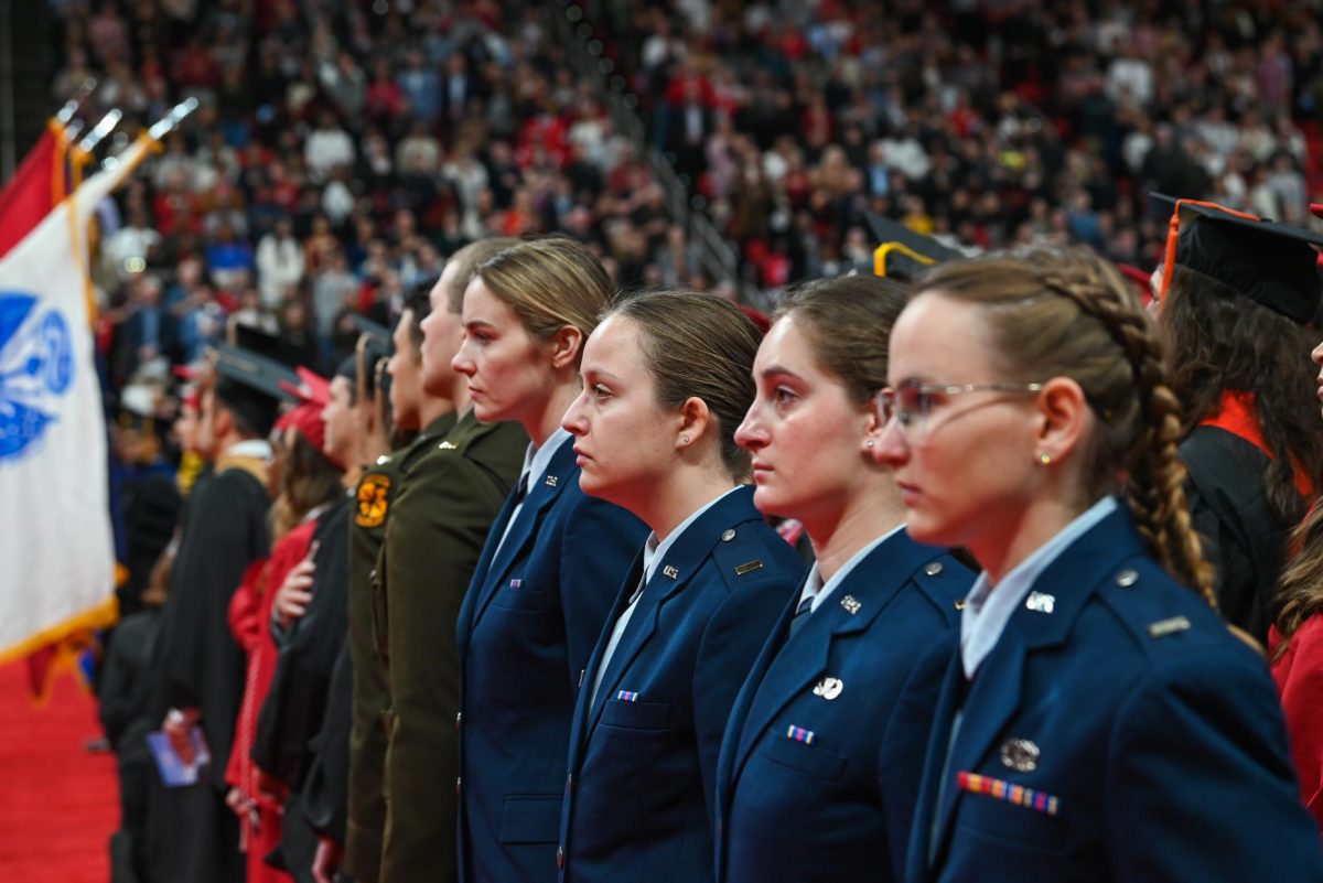 Members of ROTC stand at attention for the national anthem performed by the Grains of Time during the Fall Commencement Ceremony in the Lenovo Center on Saturday, Dec. 13, 2025. The national anthem was sung by the Grains of Time acapella group.