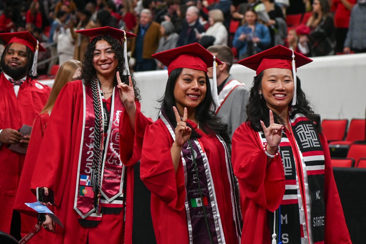 Sisters of the Epsilon Nu chapter of Lambda Theta Alpha Rebecca Hernandez, a fourth-year studying communications and Andrea Martinez, a fourth-year studying criminology, and sister of the Alpha Epsilon chapter of Kappa Phi Lambda, Jenna Rose, a fourth-year studying bioprocessing science, gesture to the camera during the Fall Commencement Ceremony in the Lenovo Center on Saturday, Dec. 13, 2025. The Fall Commencement awarded 3,498 degrees to 3,384 graduates.