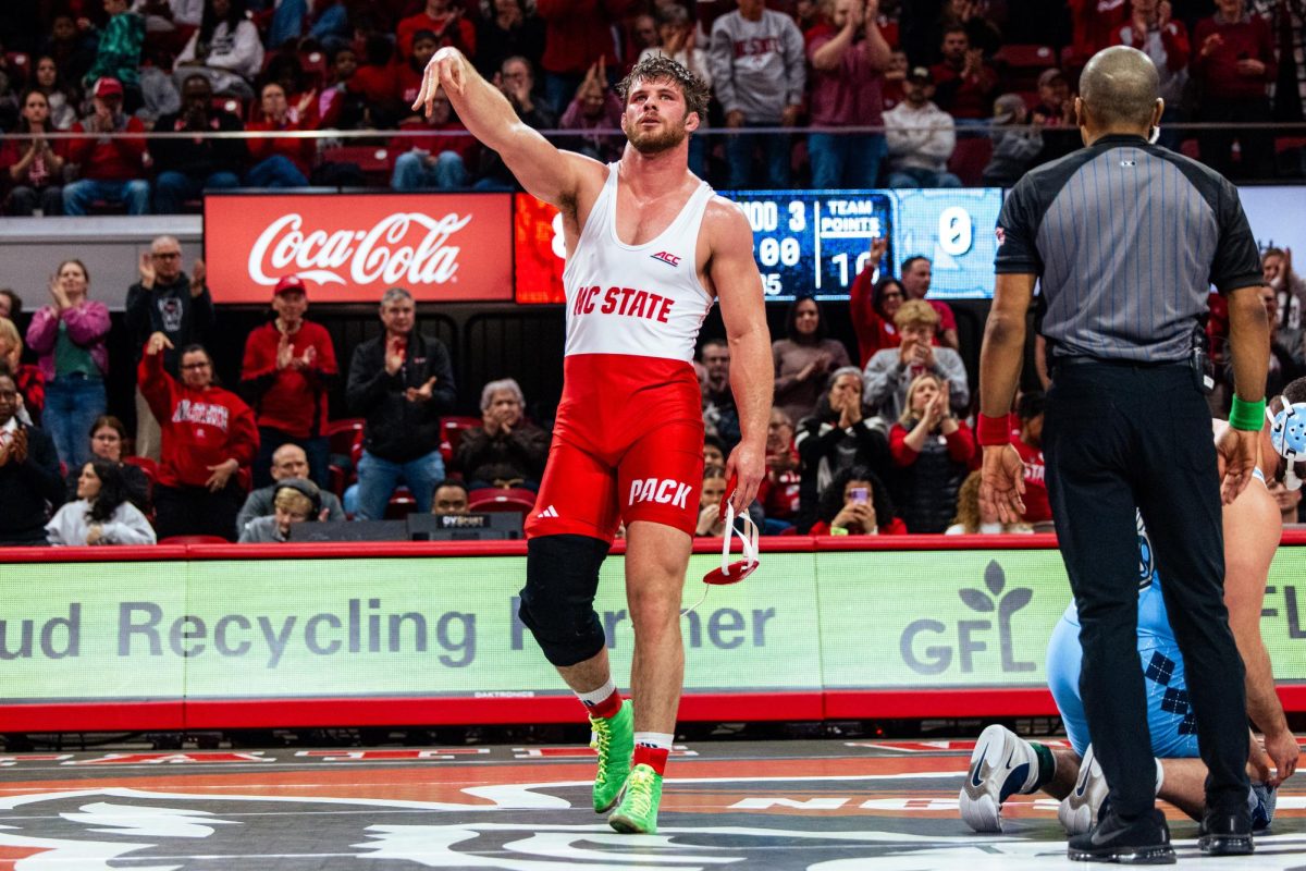 Sixth-year Isaac Trumble flips three fingers upside down in celebration after the wrestling match against UNC-Chapel Hill in Reynolds Coliseum on Friday, Jan. 23, 2026. Trumble ranked #2 won the 285 bout over #28 Nolan Neves by major decision 8-0. The Wolfpack beat the Tar Heels 24-10.
