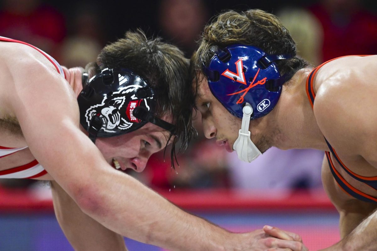 Freshman wrestler Brogan Tucker butt heads with his opponent during the wrestling match against Virginia in Reynolds Coliseum on Friday, Jan. 9, 2026. NC State beat Virginia 19-17.