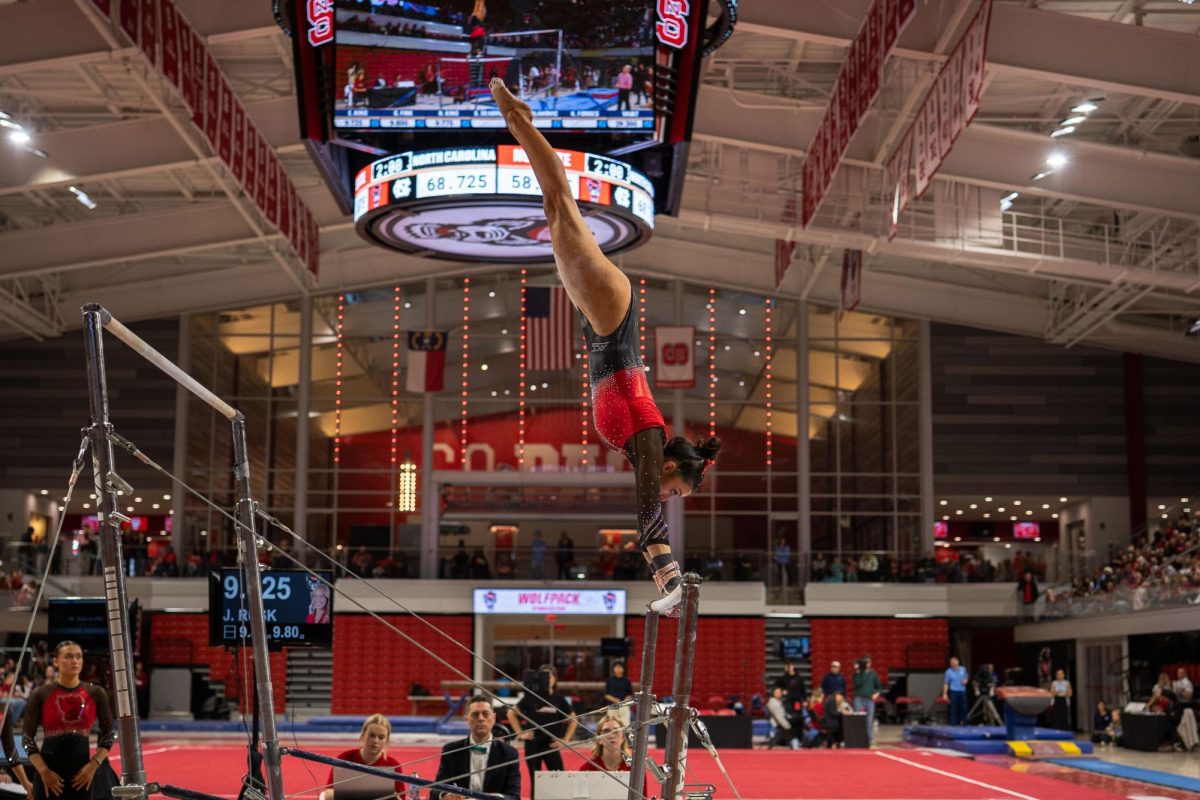 Senior Madeline Reid goes into a handstand on the bar during the meet against UNC at Reynolds Coliseum on Sunday, Feb. 8, 2025. Reid scored a 9.900 on her bar routine. NC State beat UNC 197.125-196.525.