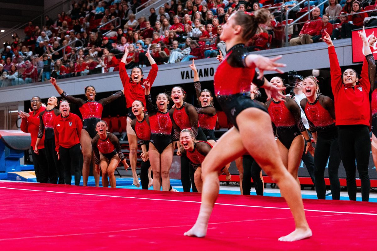 The NC State Gymnastics team cheers on junior Elle Hadrick during her floor routine during the meet against UNC at Reynolds Coliseum on Sunday, Feb. 8, 2025. Hadrick scored a 9.850 on her floor routine. The Wolfpack beat the Tar Heels 197.125-196.525.