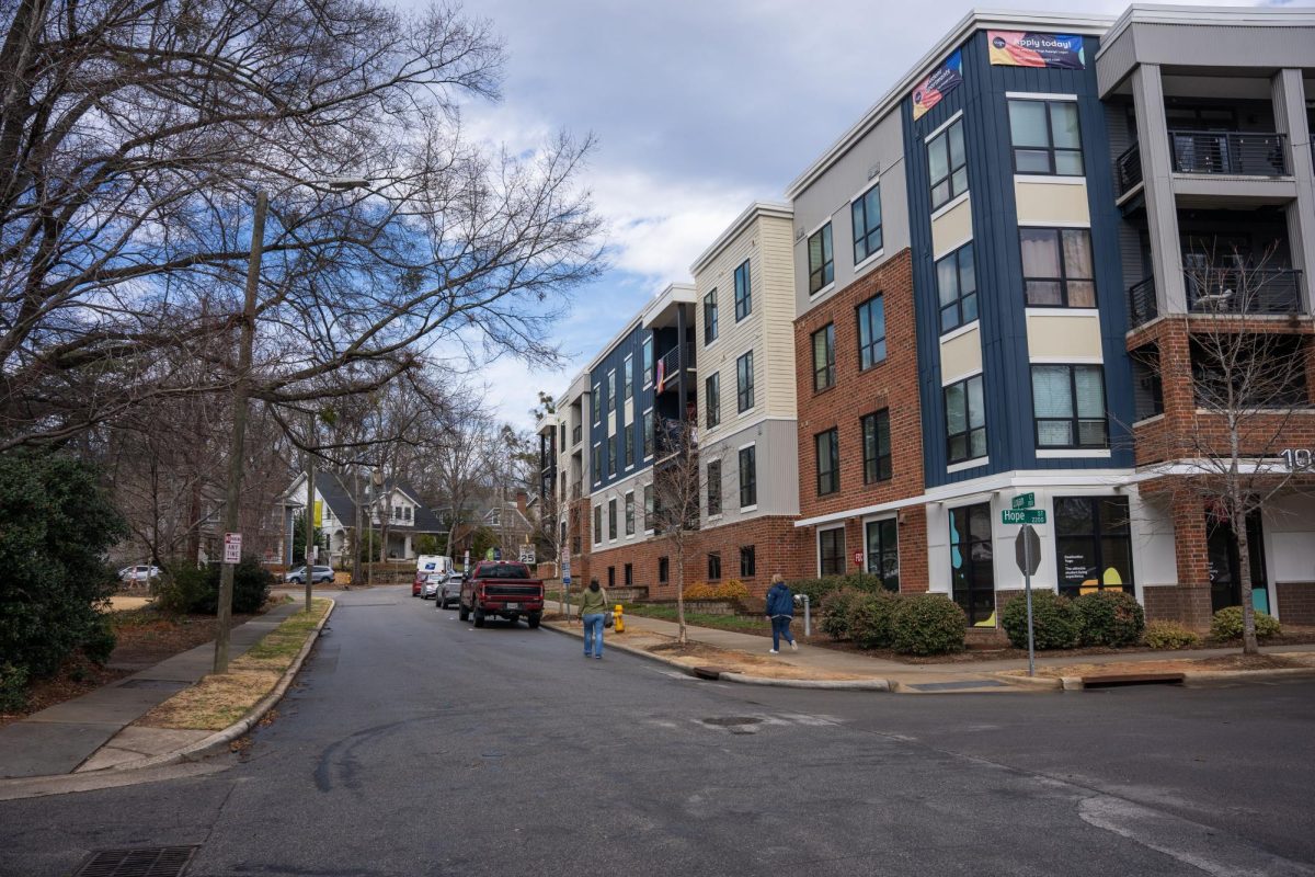 An apartment complex developed in 2019 sits in the foreground with house behind it.