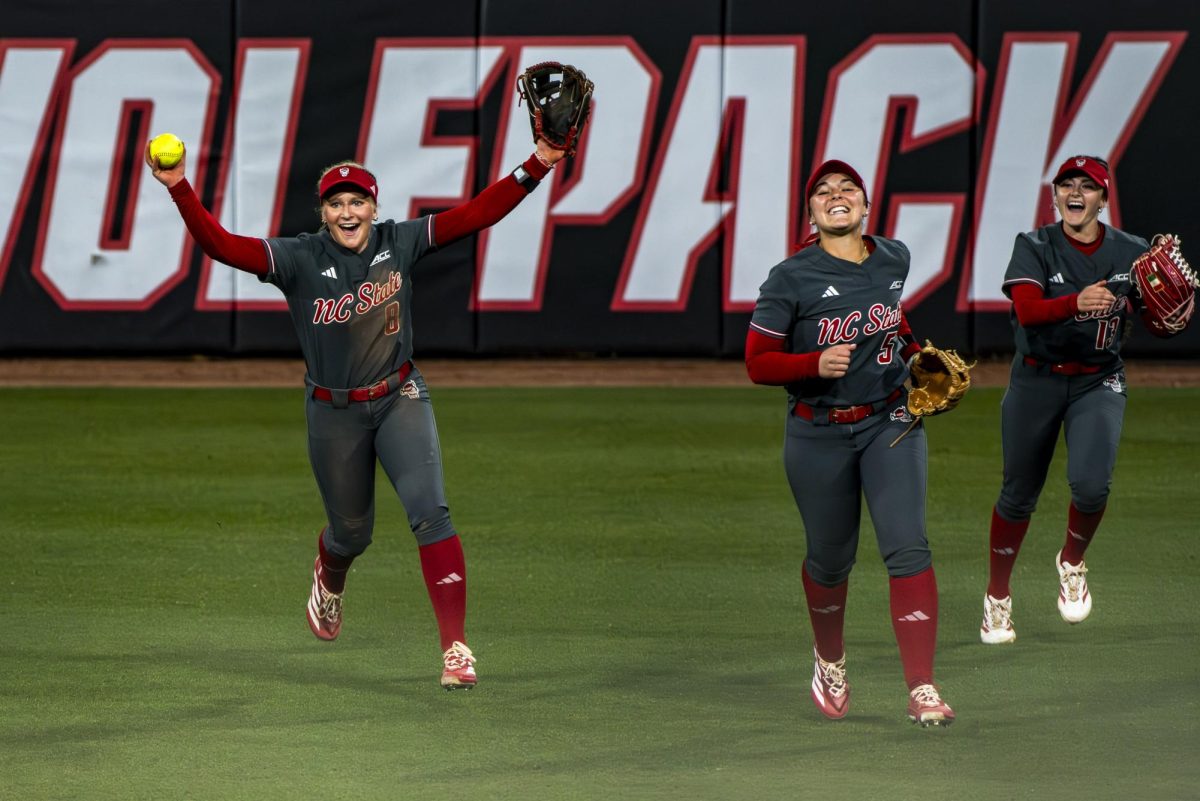 Freshman infielder Carly Short, sophomore infielder Kendall Simmers and senior outfielder Gabi Wilson celebrate after the game against Queens in Dail Softball Stadium on Tuesday, Feb. 17, 2026. The Wolfpack defeated the Royals 10-0 in five innings.