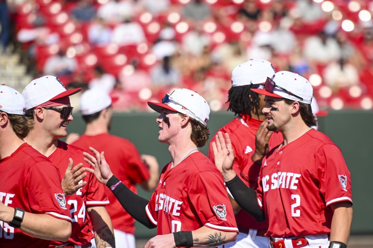 Junior outfielder Devin Mitchell welcomes junior second-baseman Luke Nixon and sophomore shortstop Mikey Ryan back into the dugout during the game against Sacred Heart in Doak Field in Dail Park on Sunday, March 1, 2026. The Wolfpack defeated the Pioneers 13-0.