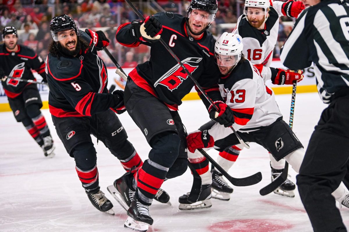 Center Jordan Staal and defenseman Jalen Chatfield rush to the puck after winning a face-off during the game versus the New Jersey Devils at the Lenovo Center on Saturday, March 28, 2026. The Canes beat the Devils 5-2.