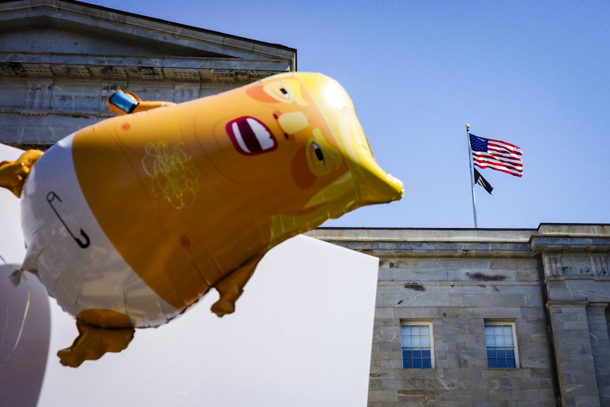 An inflatable ballon imitating Donald Trump flies in front of the American flag during the No Kings protest in Raleigh, North Carolina on Saturday, March 28, 2026.