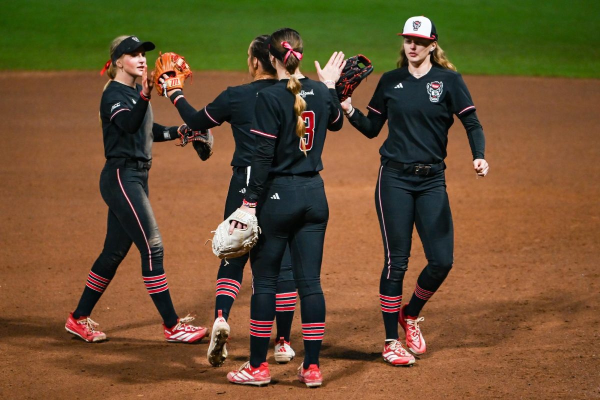 Freshman infielder Carly Short, redshirt junior right-hand pitcher Wynne Gore, Freshman utility player Morgan Talley and junior outfielder Sarah Johnson high-five at the end of the inning during the game against Toledo at Dail Softball Stadium on Saturday, Feb. 28, 2026. The Wolfpack defeated the Rockets 9-3.