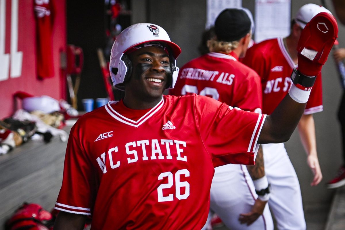 Junior infielder Sherman Johnson smiles in the dugout after running through home during the game against ECU at Doak Field at Dail Park on Tuesday, April 28, 2026. Johnson recorded two hits and one run. The Wolfpack defeated the Pirates 12-2.