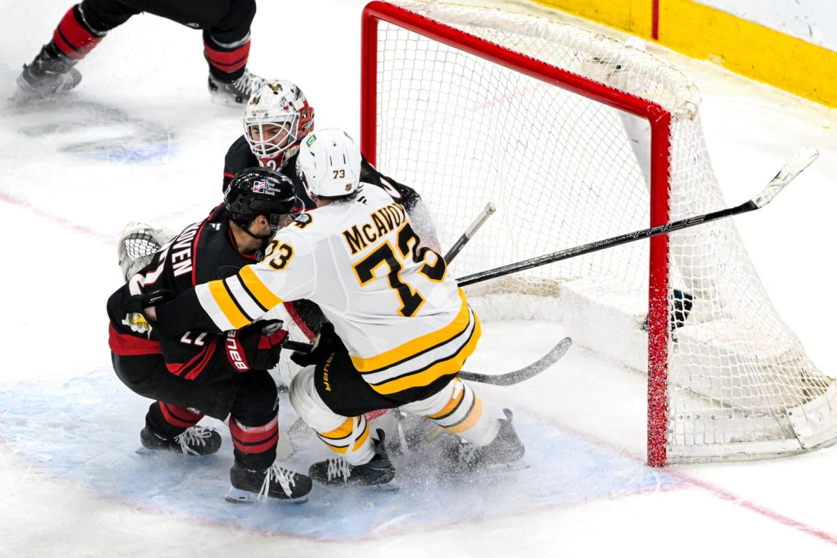 Goalie Brandon Bussi defends the net whilst center Logan Stankoven and Boston defenseman Charlie McAvoy battle each other in the crease during the game versus the Boston Bruins at the Lenovo Center on Tuesday, April 7, 2026. The Canes defeated the Bruins in OT 6-5.