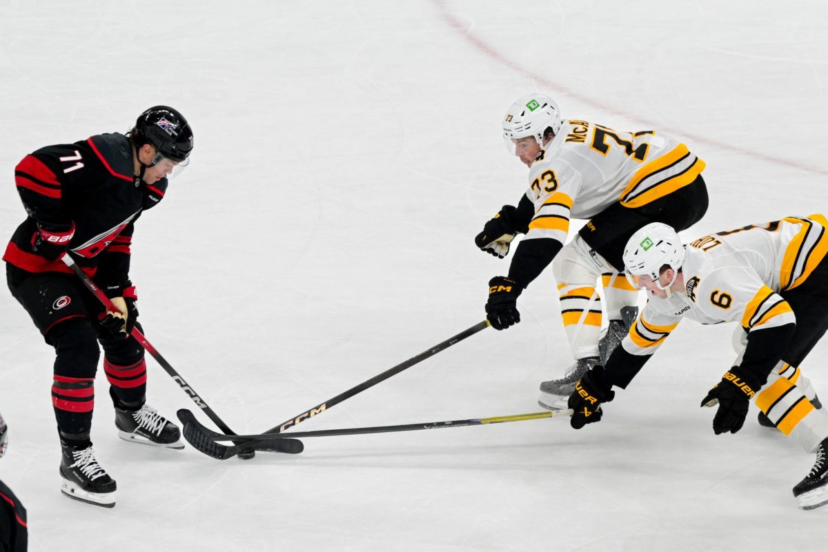 Left wing Taylor Hall fights off Boston defensemen Mason Lohrei and Charlie McAvoy for the puck during the game versus the Boston Bruins at the Lenovo Center on Tuesday, April 7, 2026. Hall had one goal. The Canes defeated the Bruins in OT 6-5.