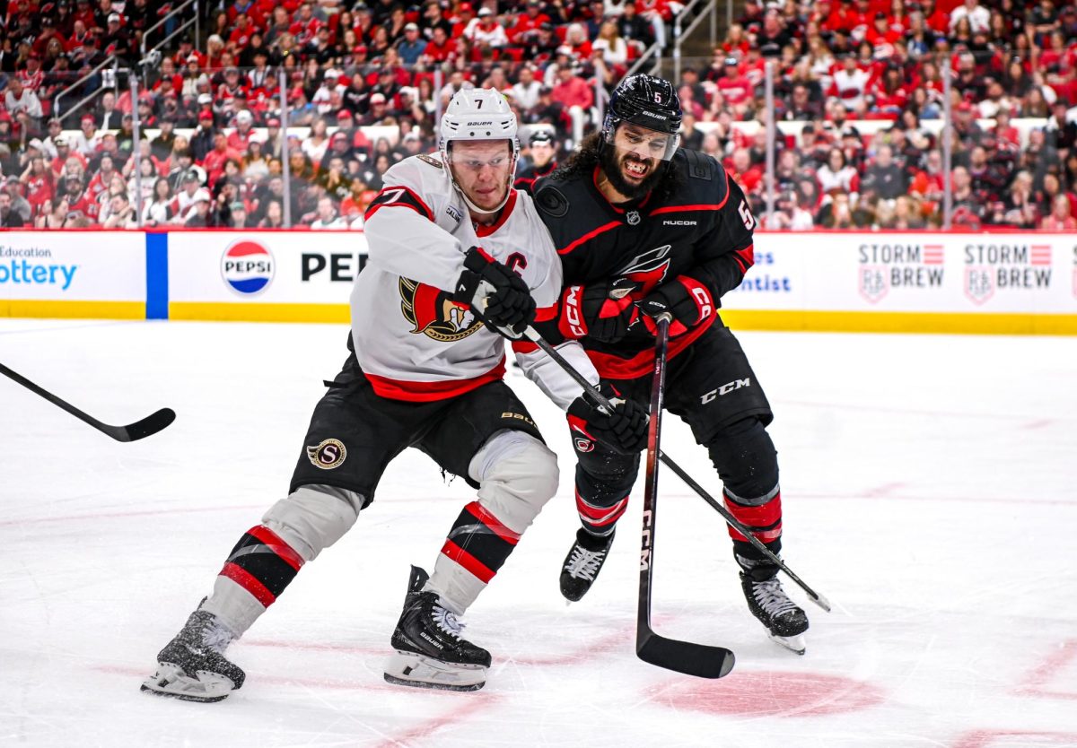 Canes defenseman Jalen Chatfield shoves Senators left wing Brady Tkachuk for the puck during Game One of the Eastern Conference Playoffs against the Ottawa Senators at the Lenovo Center on Saturday, April. 18, 2026. The Hurricanes defeated the Senators 2-0.