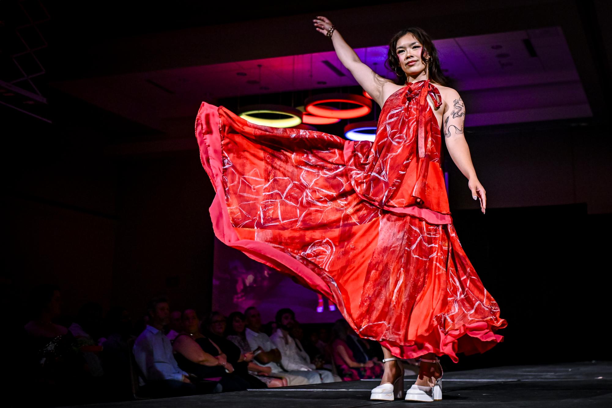 A model flings her dress in the air during the Emerging Designers Runway Show and Textile Showcase at Talley State Ballroom on Saturday, April 25, 2026. This model is wearing a piece from the Oh the Places You'll Go collection by Lainey Volz, a fourth-year studying fashion and textile design.