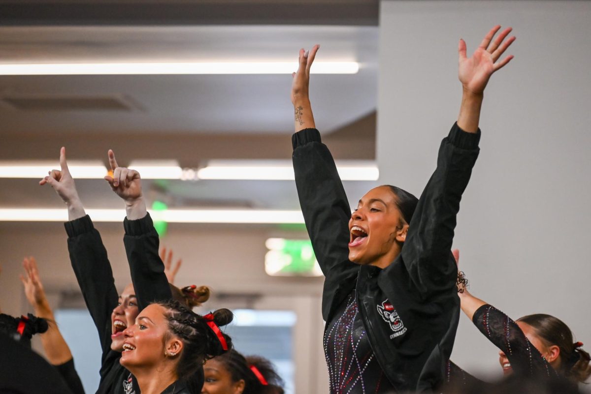 Sophomore Jenna Rusk, freshman Autumn Rusk and sophomore Ava Myers cheer on teammates at the NCAA Regional meet against Arkansas, Mizzou, and Maryland at Memorial Coliseum on Friday, Apr. 3, 2026. The Wolfpack fell to the Razorbacks and Tigers with a score of 195.700, marking the end of their 2026 season.