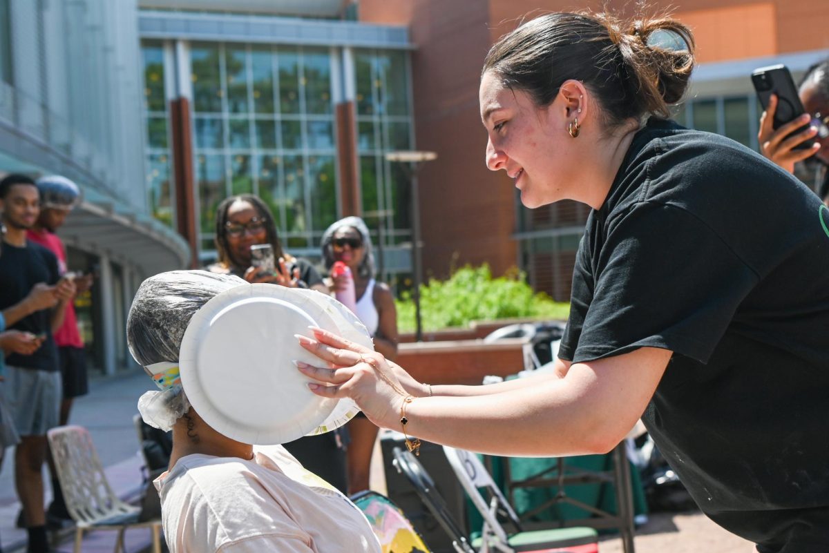 Farah Honiene, a fourth-year student studying business marketing, uses two plates to pie Gigi Davis, a third-year student studying communications, during the Pie BSB Eboard event at Stafford Commons on Tuesday, April. 17, 2026. The pie the Black Student Board Eboard event is part of Pan-African Week, a weeklong celebration of Pan-Africanism that promotes unity among students through fun activities designed for the black community.