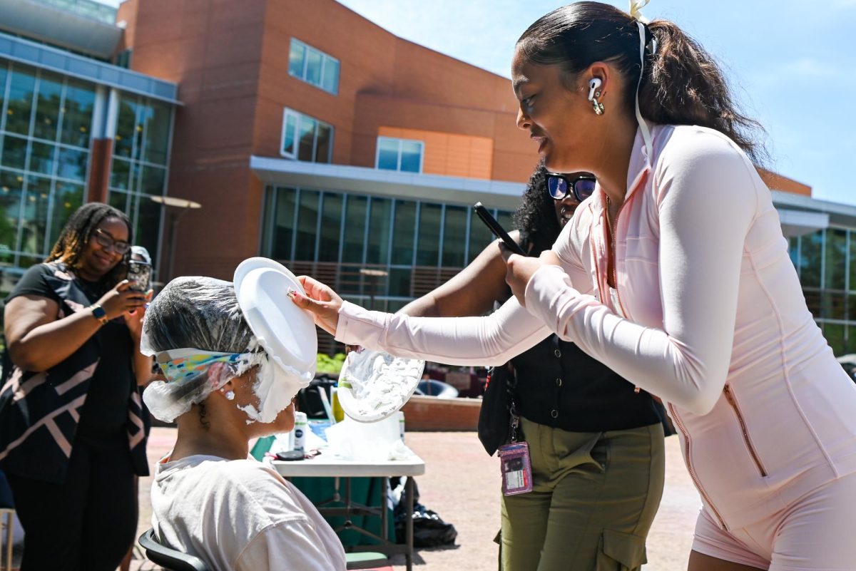 Mary-Riley Locklear, a second-year studying criminology, wipes plate on Gigi Davis, a third-year studying communications, face during the Pie BSB Eboard event at Stafford Commons on Tuesday, April. 17, 2026. The pie the Black Student Board Eboard event is part of Pan-African Week, a weeklong celebration of Pan-Africanism that promotes unity among students through fun activities designed for the black community.