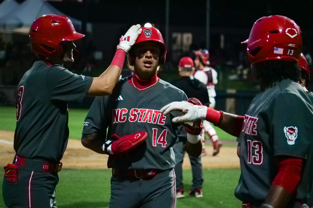 Sophomore outfielder Ty Head is greeted by congratulations after scoring a run by teammates freshman infielder Christian Serrano and junior outfielder Andrew Wiggins during the game against Stanford at Klein Field at Sunken Diamond on Friday, May 8, 2026. The Wolfpack fell to the Cardinal 6-5. 