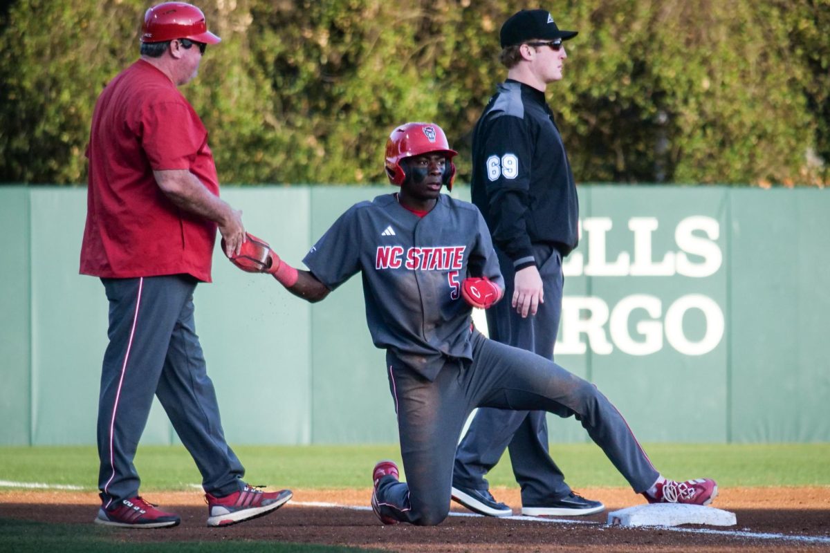 Junior infielder Sherman Johnson high-fives third base coach Chris Hart after sliding into third during the game against Stanford at Klein Field at Sunken Diamond on Friday, May 8, 2026. Johnson was 3-for-3 with three RBIs. The Wolfpack fell to the Cardinal 6-5. 