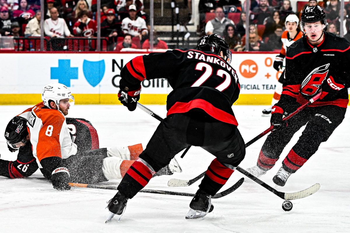 Logan Stankoven gains possession of the puck amidst the collision of Flyers defenseman Cam York and Canes defenseman Sean Walker during Game One of Round Two in the Eastern Conference Playoffs against the Philadelphia Flyers at the Lenovo Center on Saturday, May. 2, 2026.  The Hurricanes defeated the Flyers 3-0.
