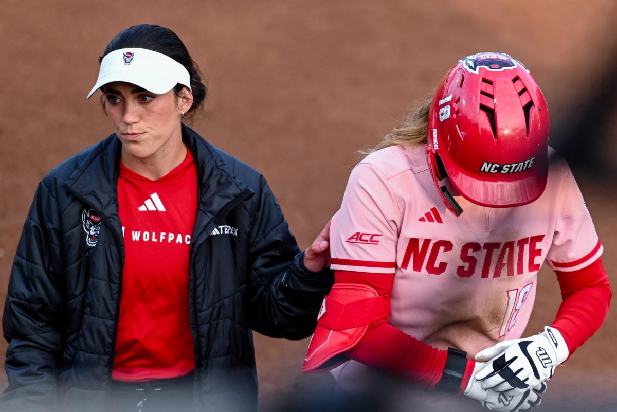 Assistant coach Grayson Radcliffe checks on junior outfielder Sarah Johnson after sliding during the game against Louisville at Dail Softball Stadium on Friday, May 1, 2026. The Wolfpack fell to the Cardinals 5-1.