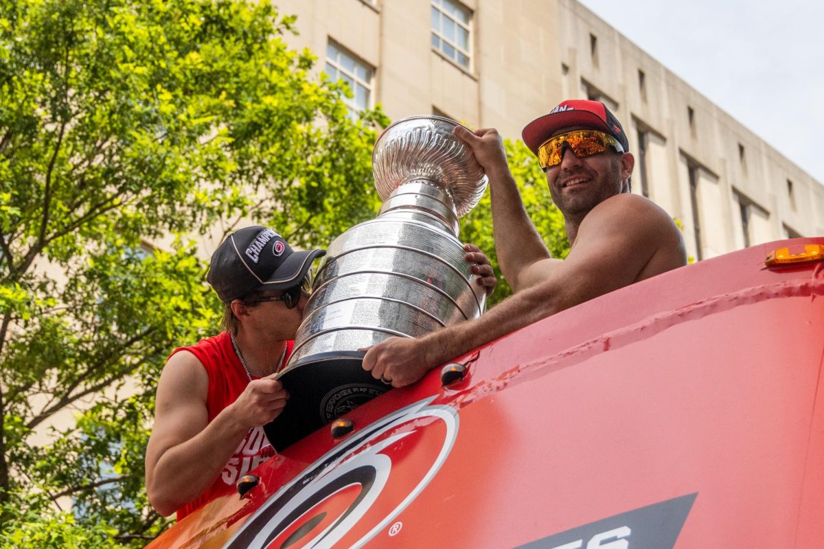 Center Sebastian Aho kisses the Stanley Cup while left wing Jordan Martinook holds it during the Championship Celebration in downtown Raleigh on Saturday, June 20, 2026. The duo helped secure the final victory of the postseason run earlier in the week.
