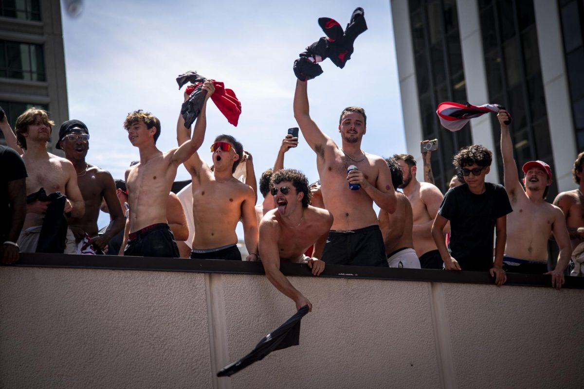Thomas Gilbert (center), a third-year studying computer engineering, sticks out his tongue while taking part in a "tarps off" celebration during the Carolina Hurricanes Championship Celebration in downtown Raleigh on Saturday, June 20, 2026.