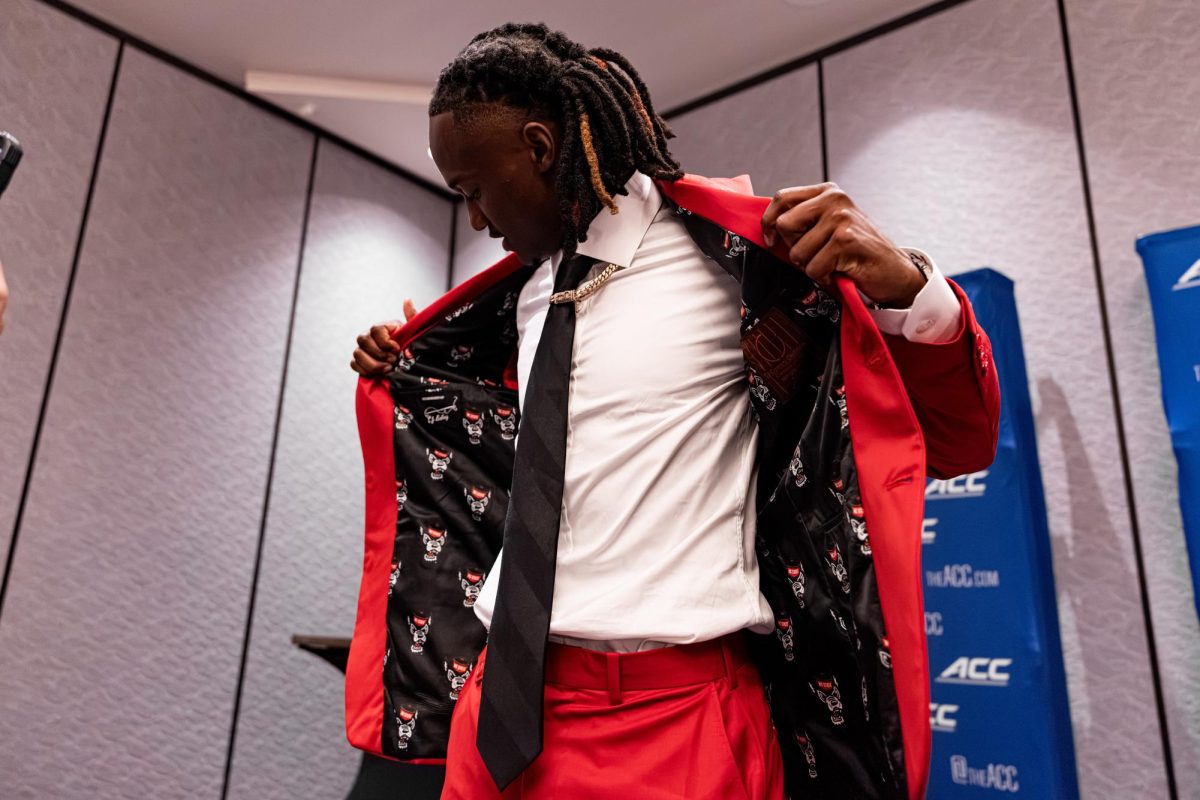 Junior quarterback CJ Bailey shows the custom Wolfpack-themed lining of his suit jacket during the ACC Football Kickoff at the Hilton Charlotte Uptown in Charlotte, North Carolina, on July 22, 2026. Bailey represented NC State at the conference’s annual preseason media event before his third season leading the Wolfpack offense.
